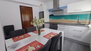 A modern kitchen with a view of the sea, a dining table with placemats, and a vase of flowers. - Apartment with sea view (Campelo)