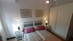 A bedroom with a bed, two bedside tables, a nightstand, a wardrobe, and two wall-mounted light fixtures. - Apartment with sea view (Campelo)