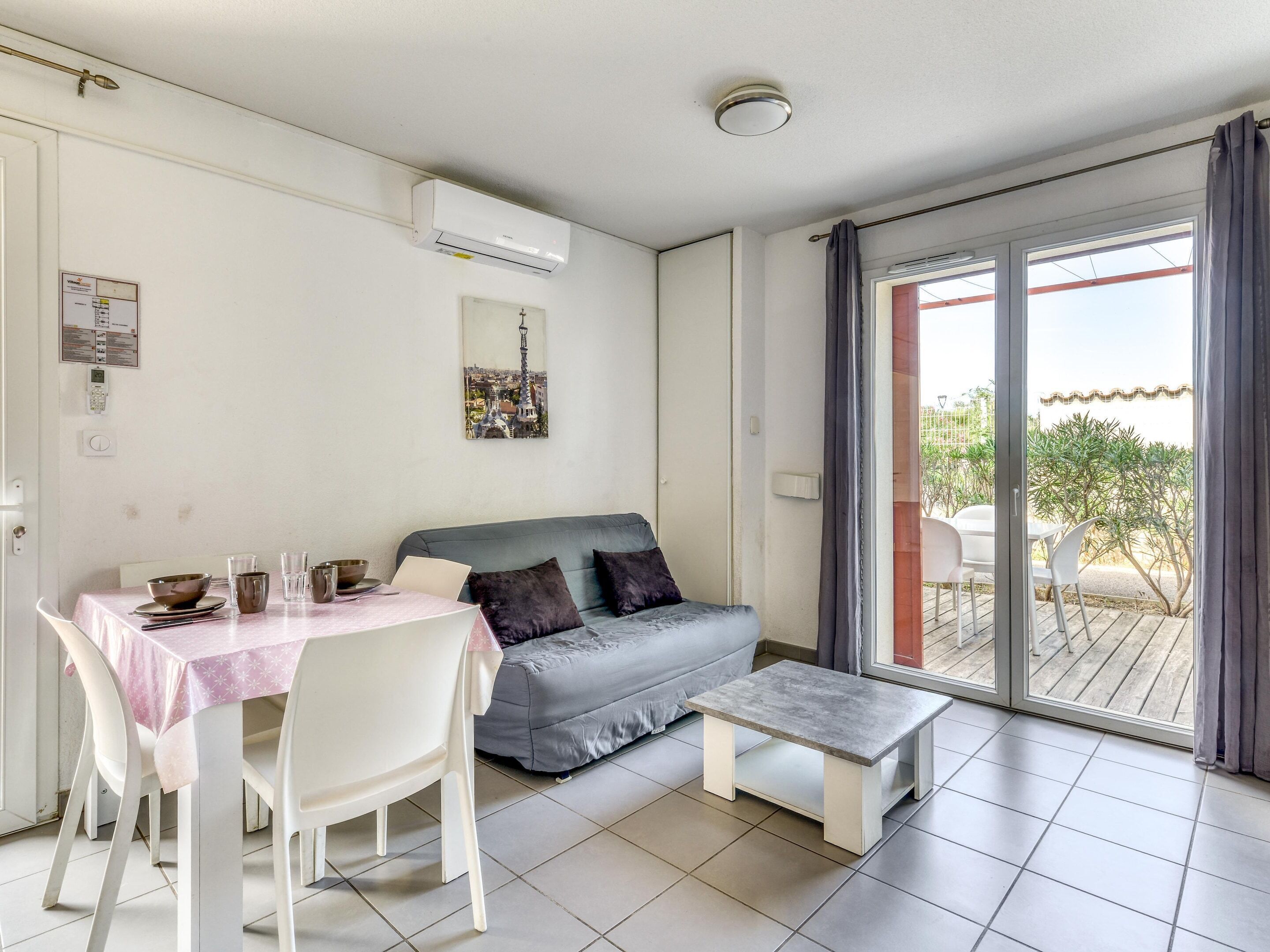 A room with a dining table, chairs, a sofa, a small coffee table, and a sliding glass door leading to an outdoor area.