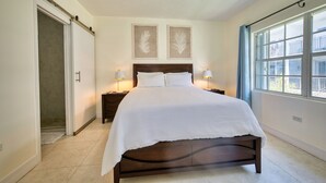 A bedroom with a bed, bedside lamps, a ceiling fan, and two wall-mounted leaf artwork. - 2BR/2BA Peaceful Retreat, Patio, Walk to Beach (West Bay)