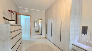 Ein Flur mit großem Spiegel, Kleiderschrank und einer Zimmerpflanze.