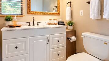 A bathroom with a white toilet, a vanity with a mirror, and a towel rack.