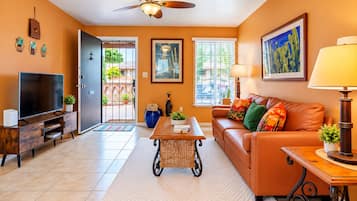 A living room with a television, sofa, coffee table, and a ceiling fan.