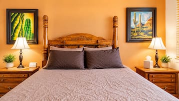 A neatly made bed with a wooden headboard, two bedside tables with lamps, and framed pictures on the walls.