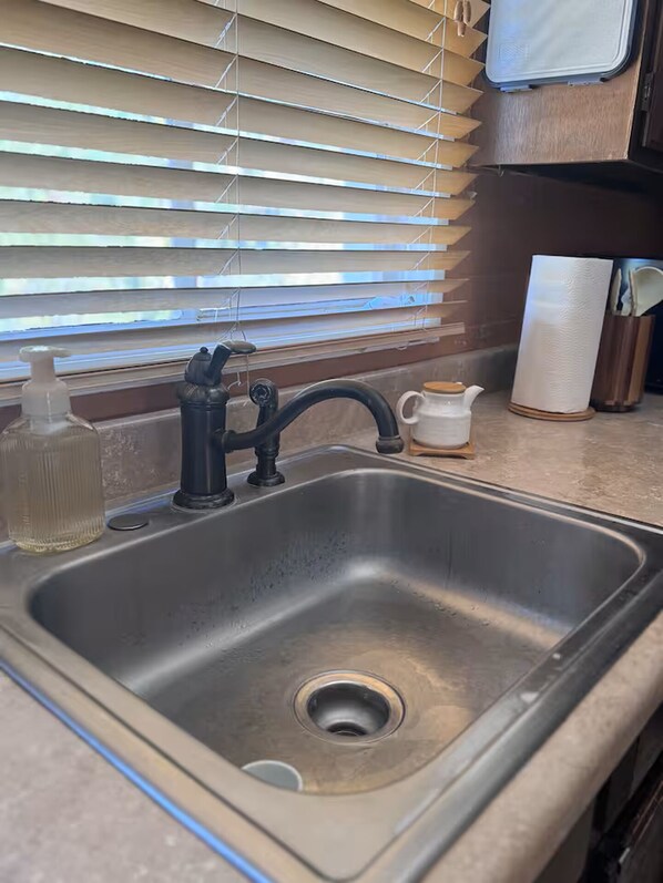 Un lavamanos de cocina con grifo, dispensador de jabón y portarrollos de papel.
