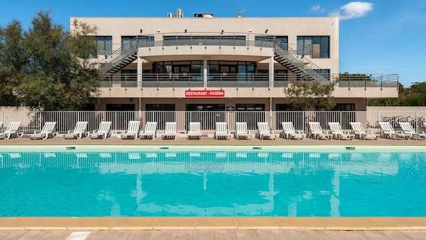 A modern building with a pool, lounge chairs, and a sign for a restaurant. - Pool View Apartment for Six (Le Grau-Du-Roi)