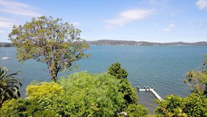 A lake with a dock, surrounded by trees and hills in the background. - Metawise Stylish 2-bedroom Home With Easy CBD Ac (Point Clare)