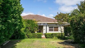 A residential house with a tiled roof, a front porch, and a well-maintained lawn. - Metawise Stylish 2-bedroom Home With Easy CBD Ac (Point Clare)