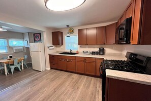 Una cocina con armarios de madera, estufa, microondas y comedor con mesa y sillas.