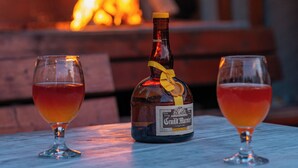 A bottle of Grand Marnier and two glasses on a table with a fire in the background. - Serxhio Apartments Golem (Golem)