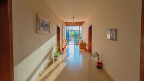 A hallway with tiled flooring, potted plants, and framed artwork on the walls. - Serxhio Apartments Golem (Golem)