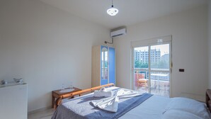 A bedroom with a bed, a desk, a wardrobe, and a balcony with a view of buildings. - Serxhio Apartments Golem (Golem)