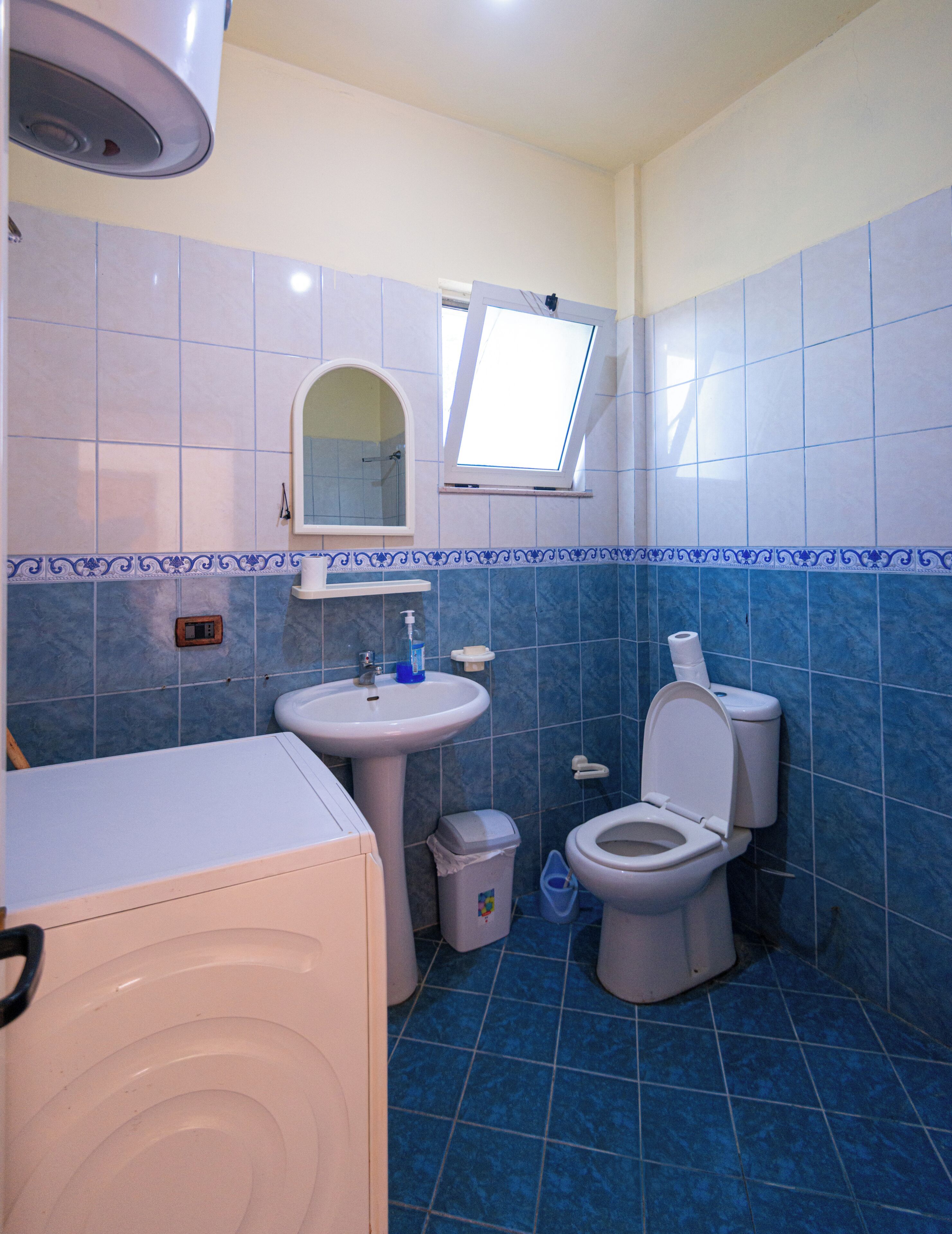 Un baño con lavamanos, inodoro y lavadora.
