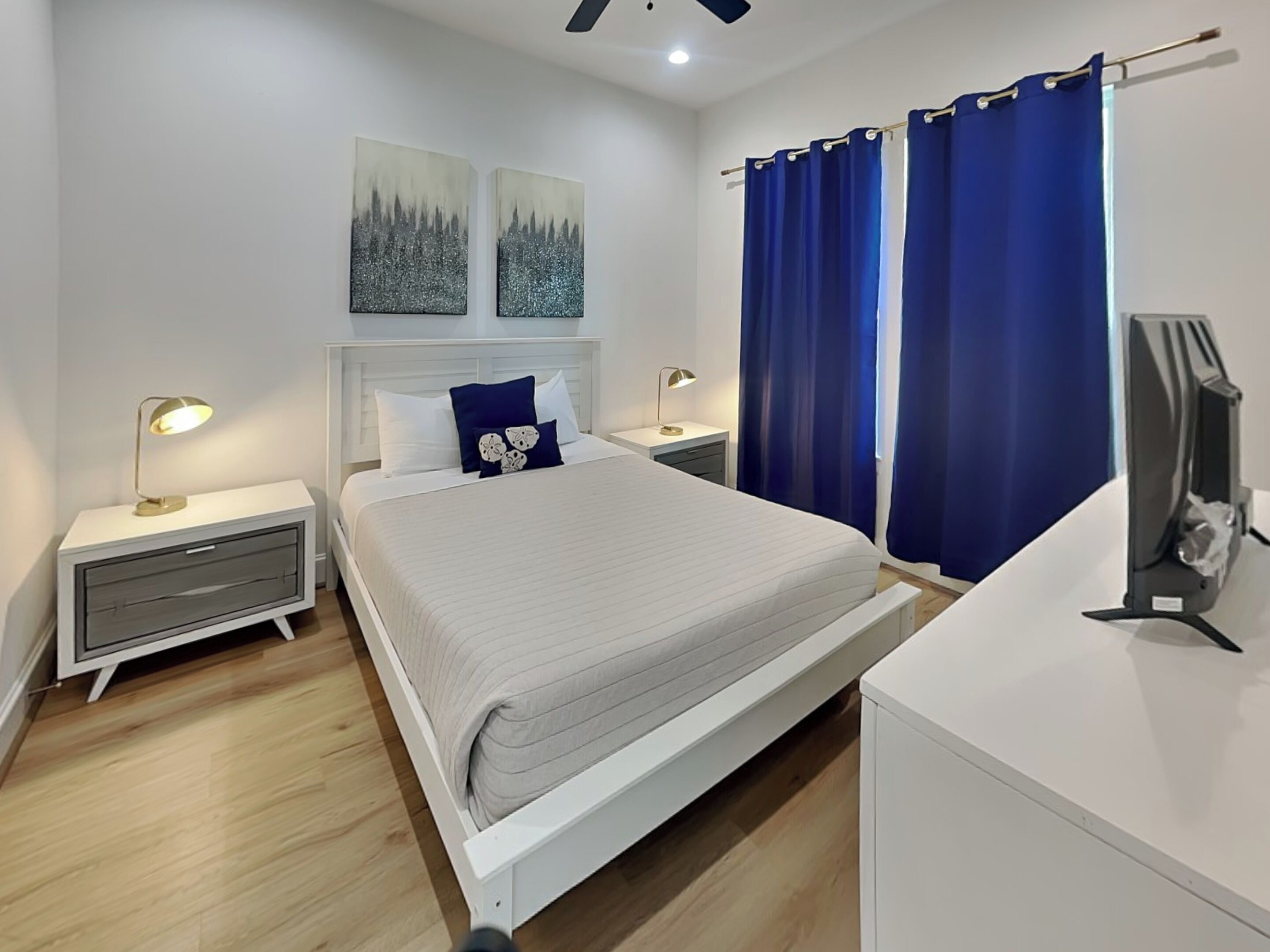 Une chambre à coucher avec un lit, des tables de chevet, un bureau et des rideaux.