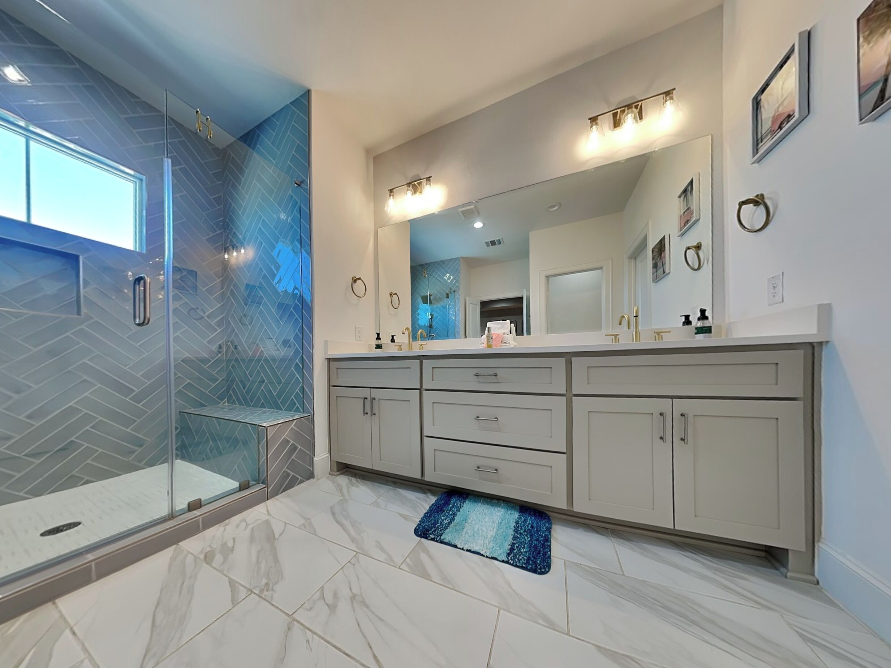 A modern bathroom with a glass shower enclosure, a large mirror, and a marble floor.