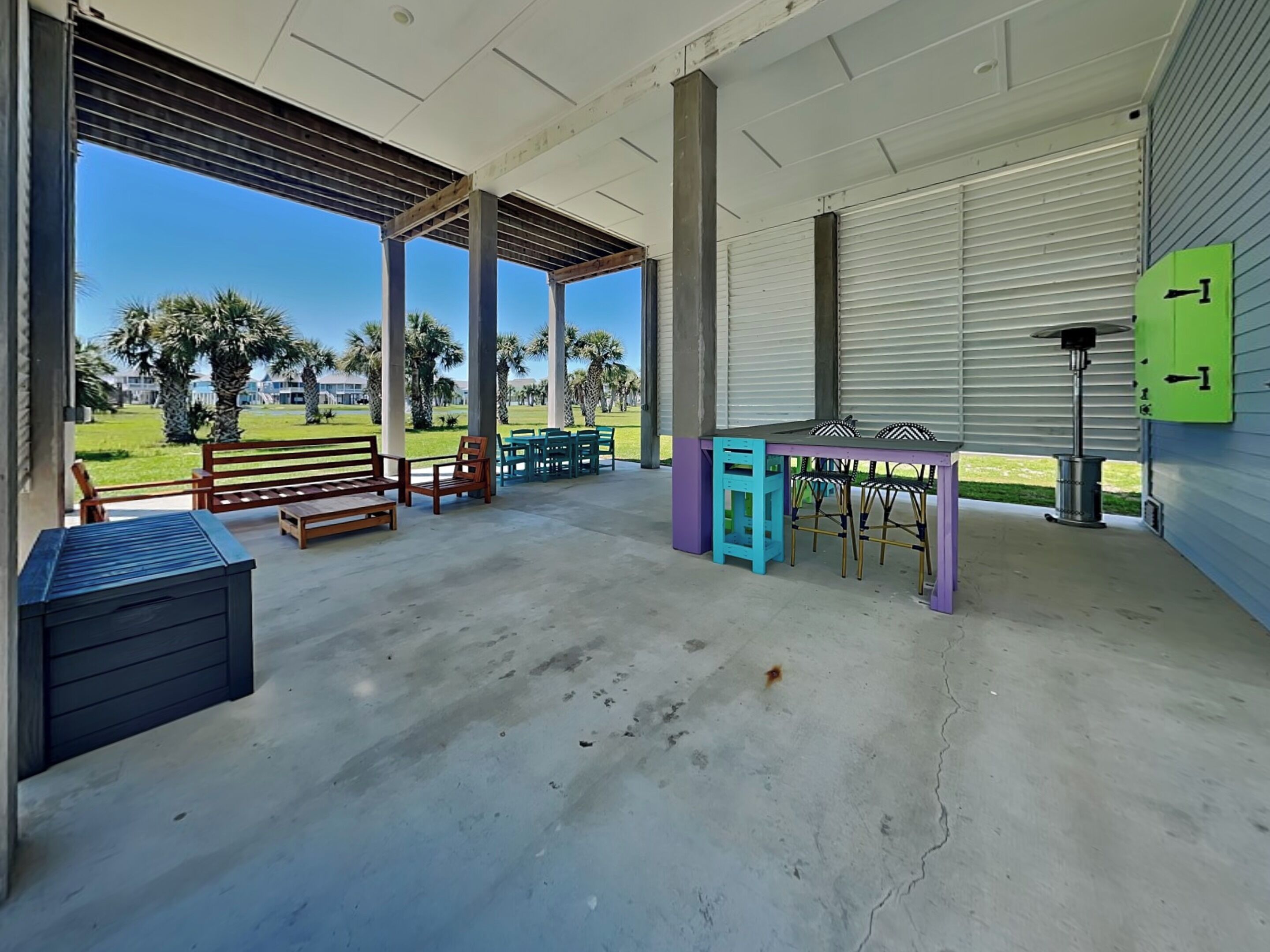 A covered outdoor seating area with tables and chairs, a bench, and a trash can.