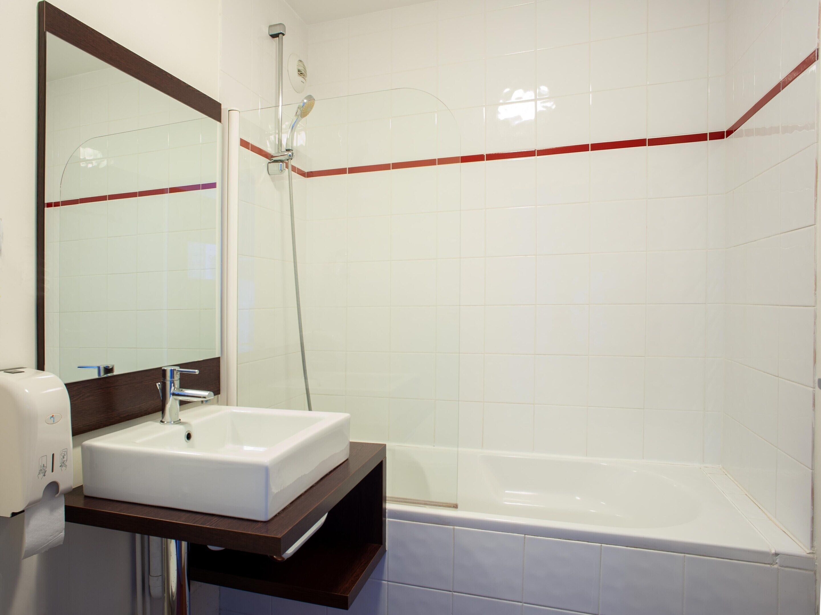 A bathroom with a white sink, a mirror, a shower, and a bathtub.