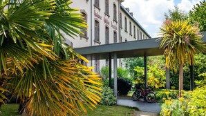A building with a sign reading 'Hotel DuPont de', surrounded by lush greenery and a bicycle parked outside. - Cozy 2-person Studio in Correze (Dinan)