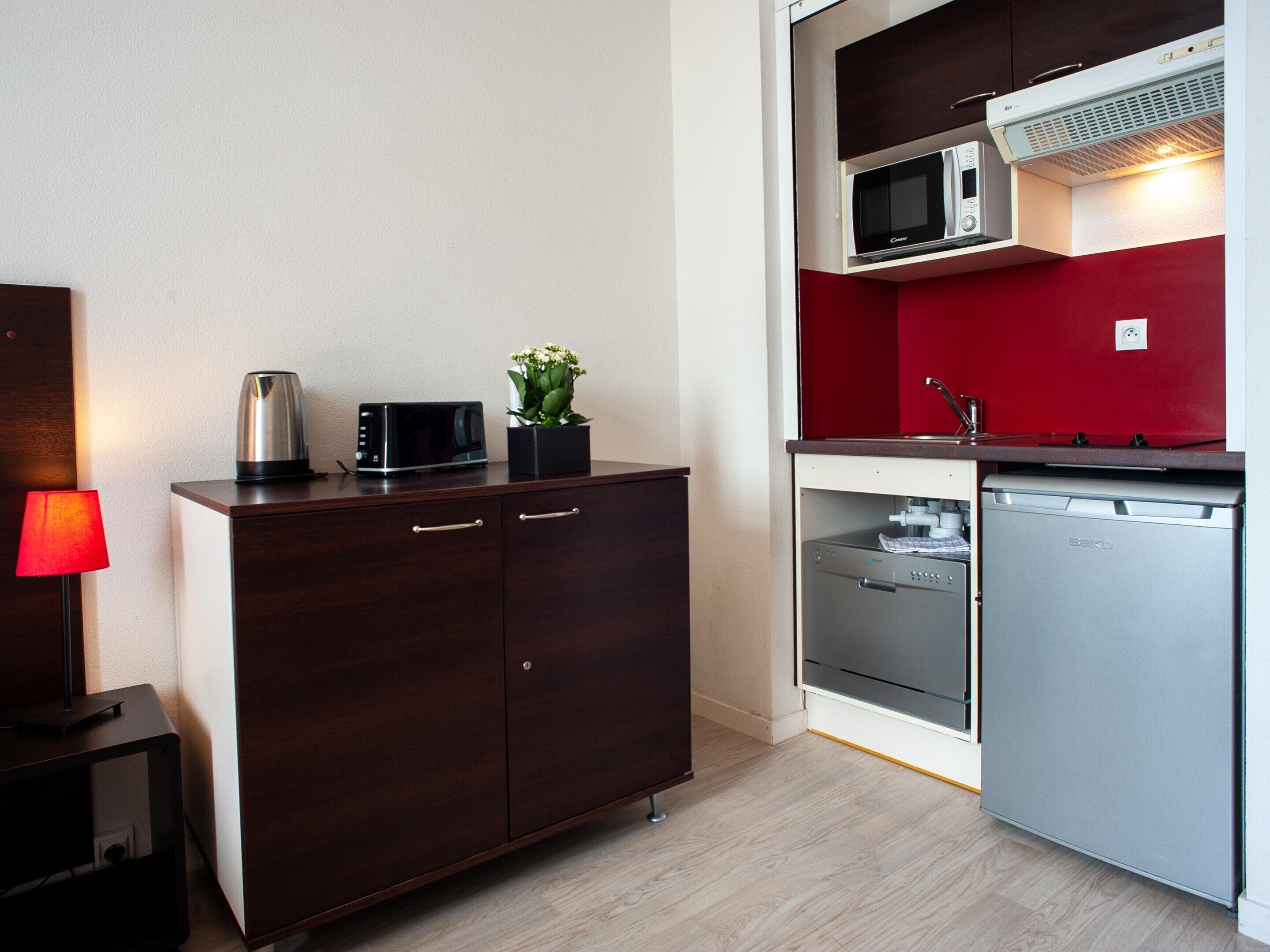 Une petite cuisine équipée d’un four à micro-ondes, d’un grille-pain et d’un petit réfrigérateur.