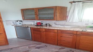 Een keuken met houten kastjes, een vaatwasser en een betegelde vloer.