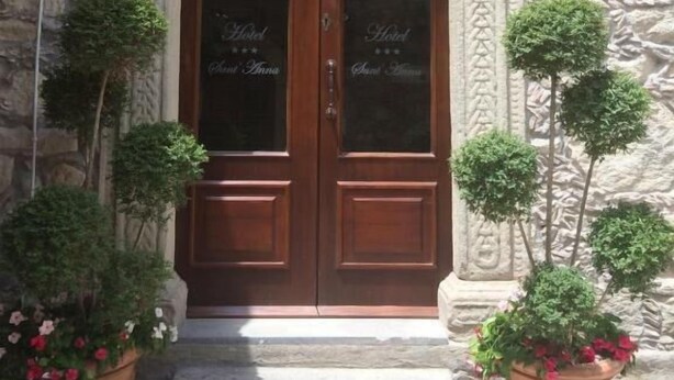 A double wooden door with glass panels, flanked by stone walls and potted plants. - hotel santt'anna (Floresta)