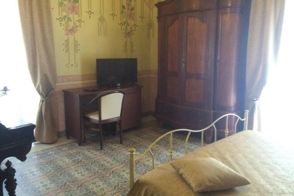 Une chambre comprenant un lit, un bureau avec une chaise, une armoire et un téléviseur.