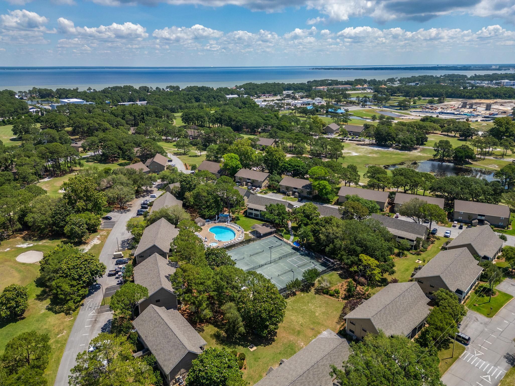 An aerial view of a residential area with houses, a swimming pool, and a tennis court.