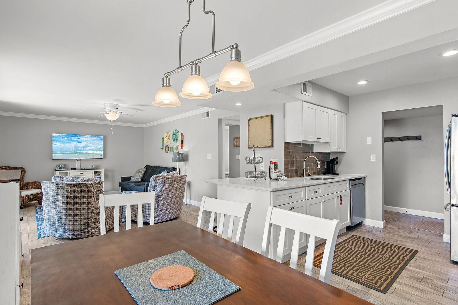 A modern kitchen with white cabinets, a built-in oven, and a stainless steel refrigerator.