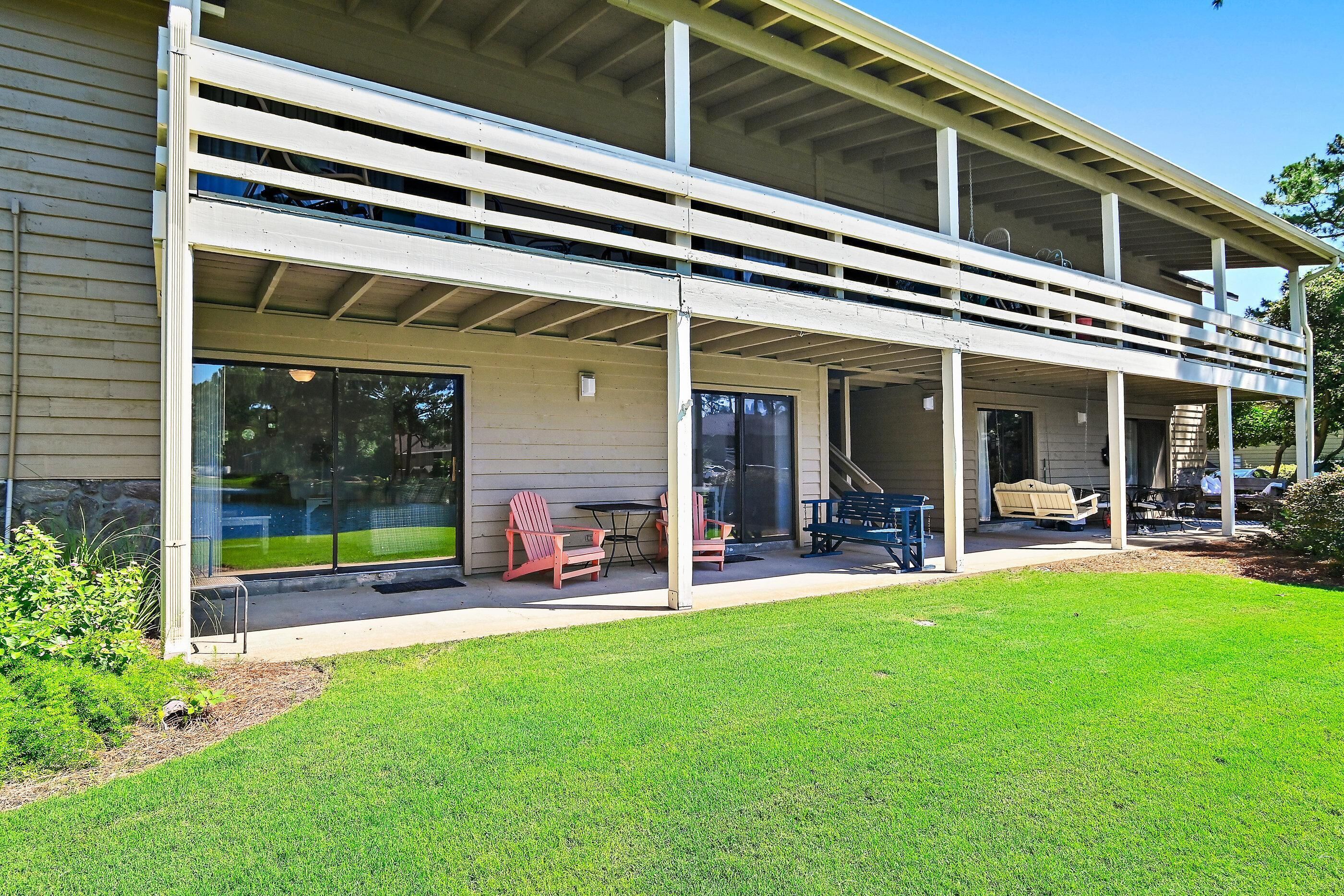 Un bâtiment à deux étages doté d’un patio couvert, de grandes fenêtres et d’un espace extérieur aménagé pour s’asseoir.