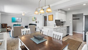 Une cuisine moderne avec des meubles blancs, un îlot central et des luminaires suspendus.