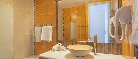 A bathroom with a bathtub, a sink with a large bowl, a mirror, and a hairdryer mounted on the wall.
