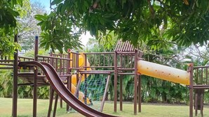 Un parc infantil amb tobogan, elements per escalar i una zona amb xarxes.