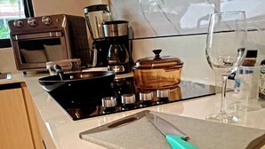 Cuina amb fogó, forn, cafetera i taula de tall amb ganivet.