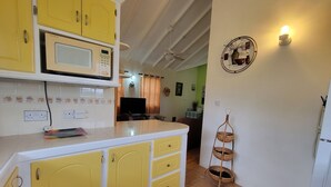 A kitchen with yellow cabinets, a microwave, and a three-tiered wicker basket.