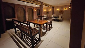 Un espace repas avec une table et des bancs en bois, un plafond à motifs et des lampes fixées au mur.