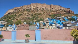 Un fort historique perché au sommet d’une colline, surplombant une ville dont les bâtiments sont peints en bleu.