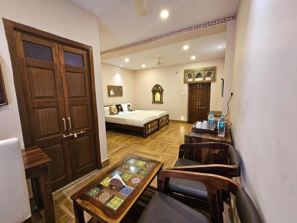 Una habitación con cama, una mesa con bandeja decorativa, un sofá y un armario de madera.