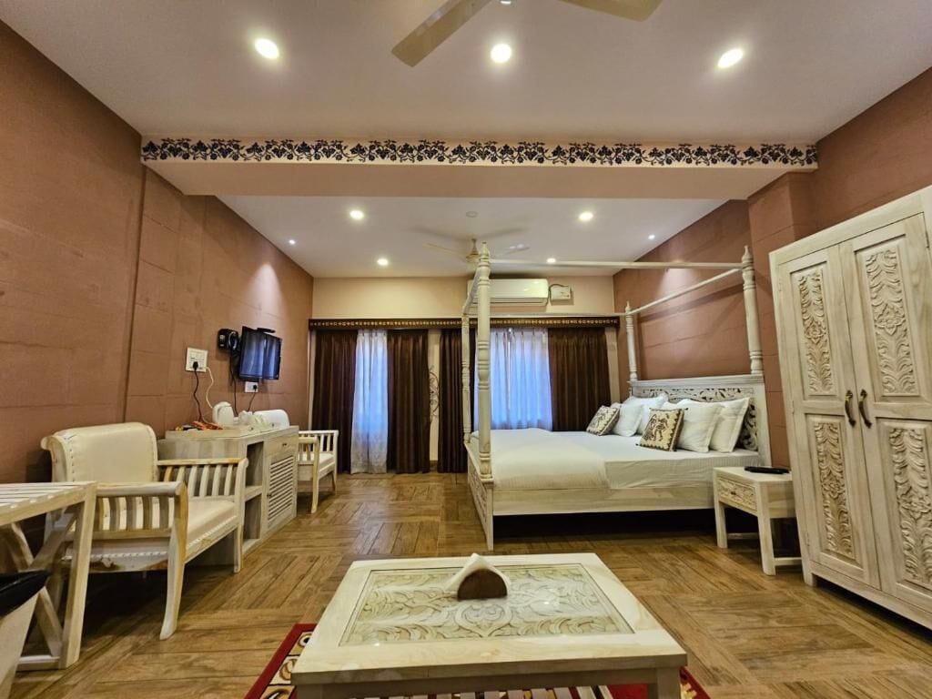 A bedroom with a four-poster bed, a television, a desk, and a cabinet.