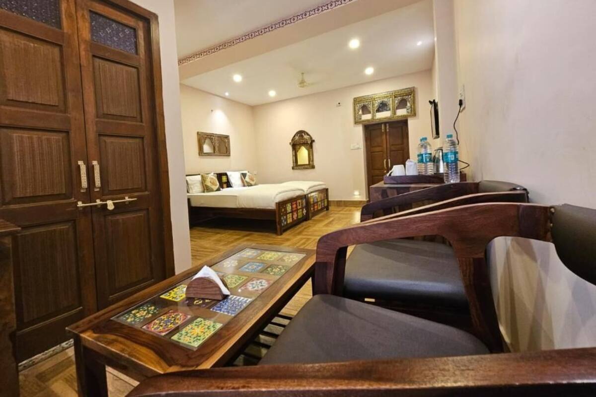Habitación de hotel con armario de madera, sofá, mesita con bandeja decorativa, cama y espejo.