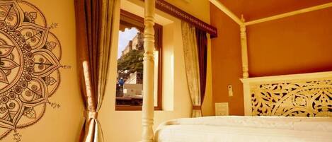Una habitación con cama con dosel, un muro decorativo con una mandala y vistas por una ventana.