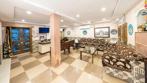 Un hall d’hôtel comprenant un comptoir d’accueil, des canapés à motifs, une table basse et un comptoir d’enregistrement.
