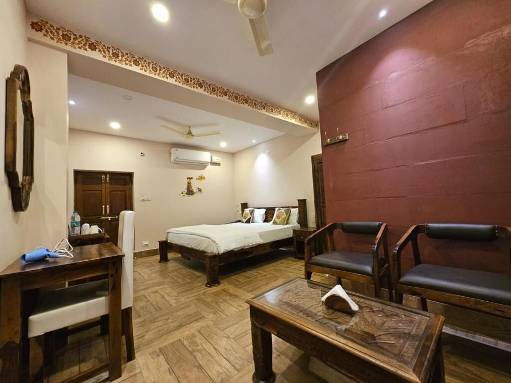 A hotel room with a bed, a desk, a chair, a sofa, and a ceiling fan.