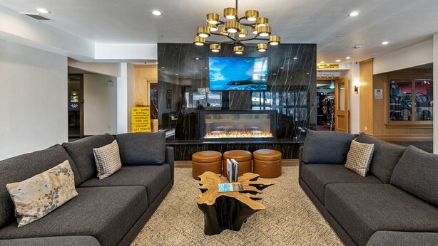 Ein modernes Wohnzimmer mit zwei Sofas, einem Kamin, einem großen Fernseher und einer Kristallleuchtre.