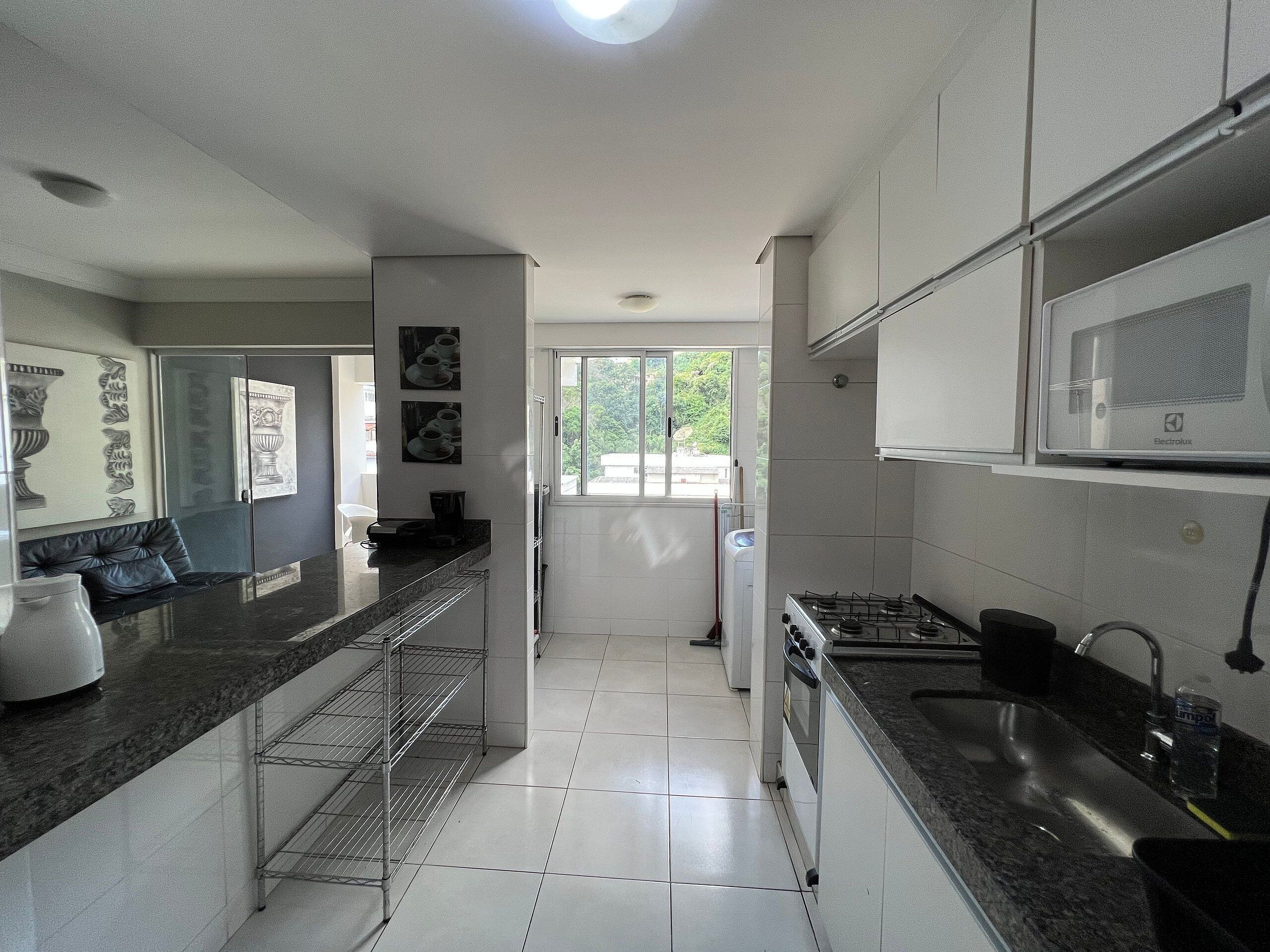 Een moderne keuken met een gasfornuis, een roestvrijstalen spoelbak en een raam met uitzicht op groen.
