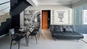 A modern living space with a staircase, dining area, sofa, and a wall with a decorative relief. - LK Santo Antônio 4 (Belo Horizonte)
