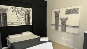 A bedroom with a bed, a nightstand, a wall-mounted artwork, and a power outlet. - LK Santo Antônio 4 (Belo Horizonte)