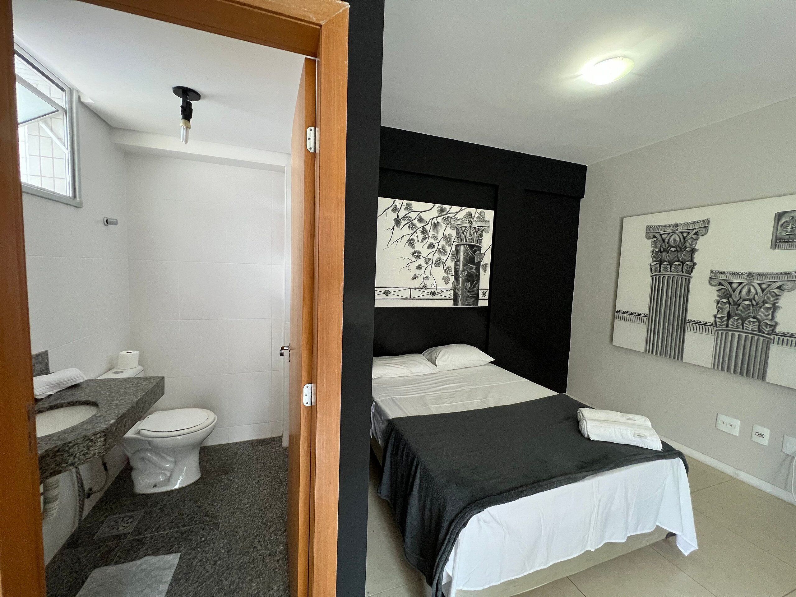 Un dormitorio con cama, un baño con inodoro y lavabo, y un pasillo con puerta.