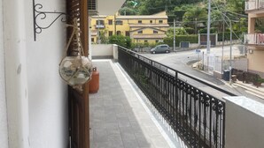 Un balcon donnant sur une rue, un immeuble à la façade jaune et une montagne en arrière-plan.