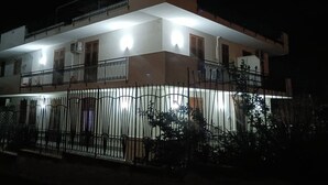 Un immeuble de deux étages doté de balcons et d’une entrée fermée par un portail.