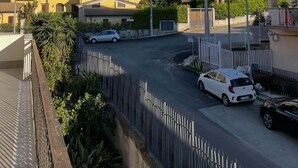 Un quartier résidentiel avec une chaîne de montagnes en arrière-plan, une voiture blanche garée dans la rue et un bâtiment jaune.